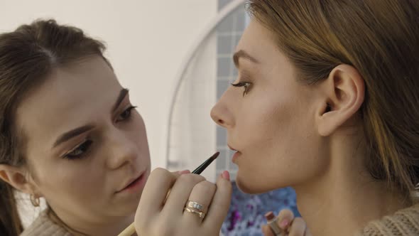 Makeup Artist Apply Pink Glitter on Lipstick with Brush on a Womans Lips