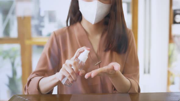 Woman Wearing Mask Applying Sanitizer in Cafe