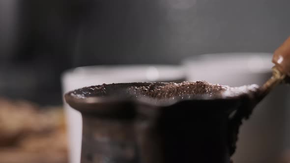 Close Up Hand Held View on Steel Turk Coffee with Two White Cups on Background