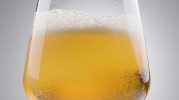 Slow motion shot co2 bubbles float around the golden beer into a glass, white background