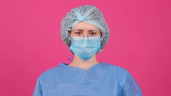 Doctor in a Blue Medical Coat Safety Glasses and Medical Cap Making Stop Gesture