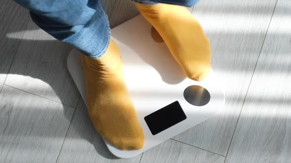 Female Legs Stepping on Floor Scales at Home.