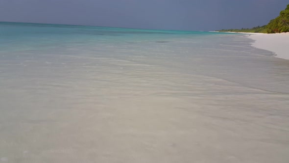 Wide angle fly over island view of a white sand paradise beach and turquoise sea background in color