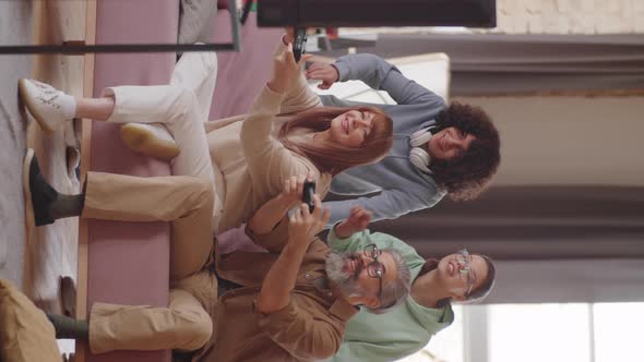 Cheerful Parents Playing Console Game with Help of Teen Kids