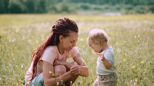 Mom with a child are sitting in a clearing or park. Parenting Maternity Joy Family Concept.