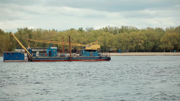 Crane Ship Sails On River At Sunset.Boat Float On Dniepr River Kiev Spring Sunset. Cargo Ship Sails