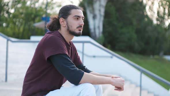 Portrait of Young Attractive Arab Man Sitting on the Stairs in Park at Sunset