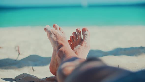 Man Lying On Beach And Moving Legs On Holiday Vacation.Happy Healthy Tourist Rest.