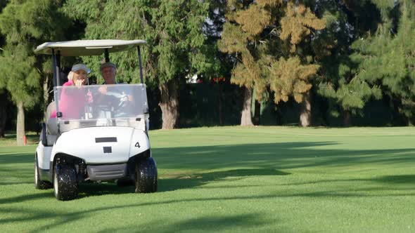 Two golfers driving in their golf buggy