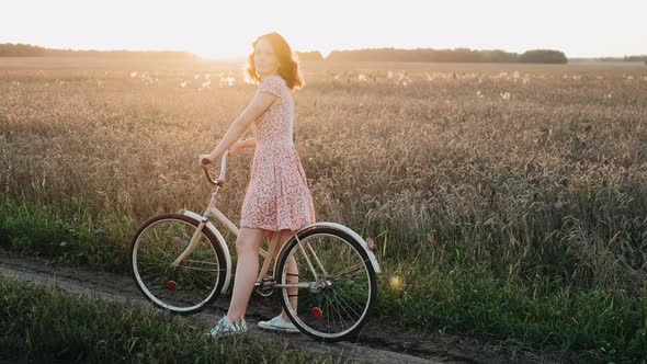 Young Romantic Beautiful Traveler Woman Girl in Dress with Retro Vintage Bicycle in Sunset
