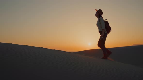 Attractive girl with retro camera walking on the sand