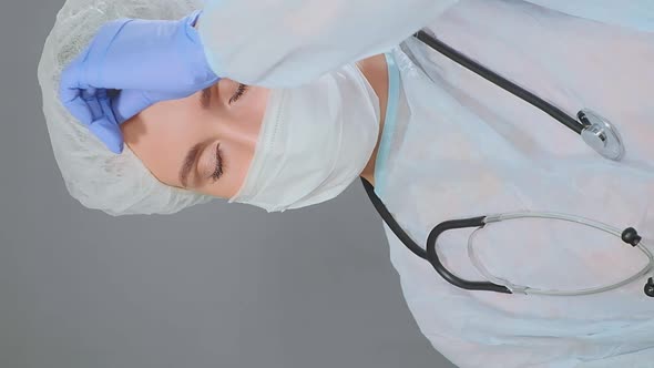 Tired Woman Doctor Takes Off White Disposable Cap and Mask