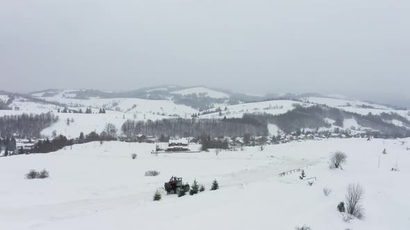 The Tractor Removes Snow From the Snowcovered Road so That the Cars Can Pass