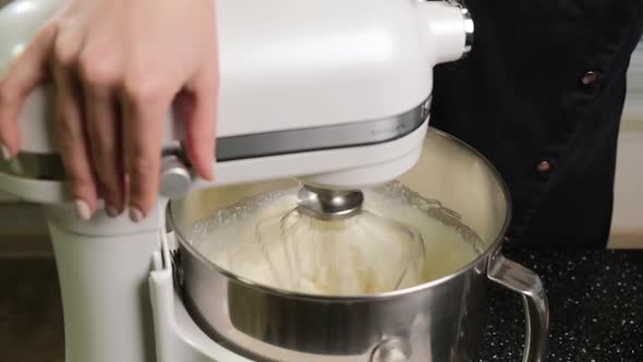 White Mixer Which is Whipping the Cream in a Stainless Bowl in the Kitchen