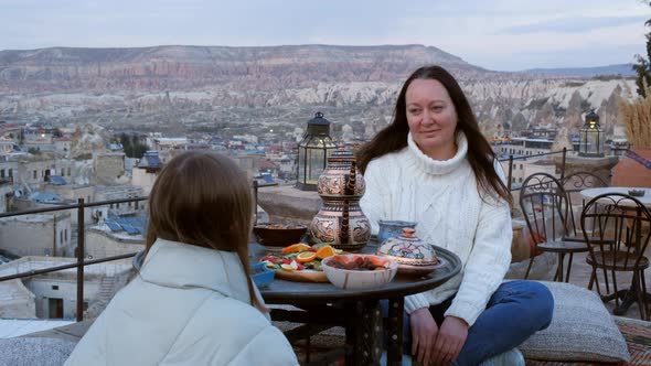 A Woman and a Girl are Sitting Opposite Each Other at a Table with Food