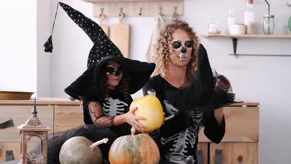 Mother and Daughter in Halloween Costumes Playing Together in Kitchen