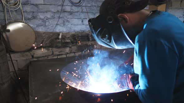 Man Welding Parts of the Metal Detail Together at Industrial Manufacture