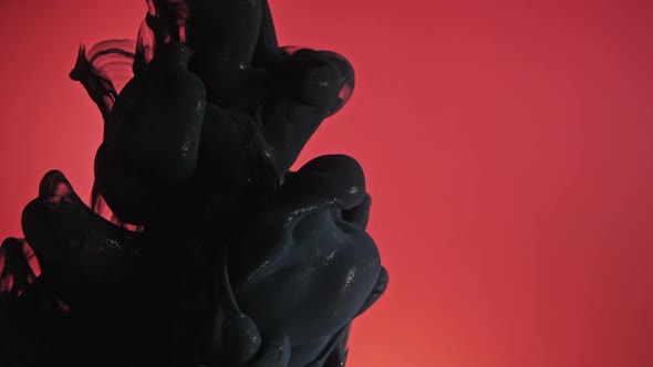 Black Nacreous Paint in Water Against Red Background. alt