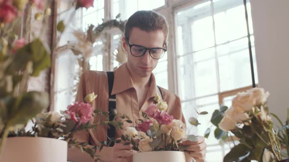 Young Male Florist Making Flower Composition and Smiling at Camera