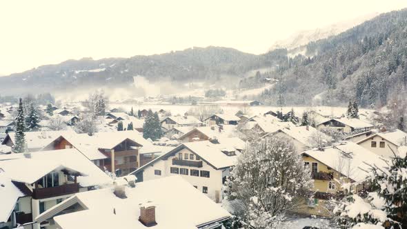 Snowy houses with smoking chimneys, Garmisch-Partenkirchen, drone shot.