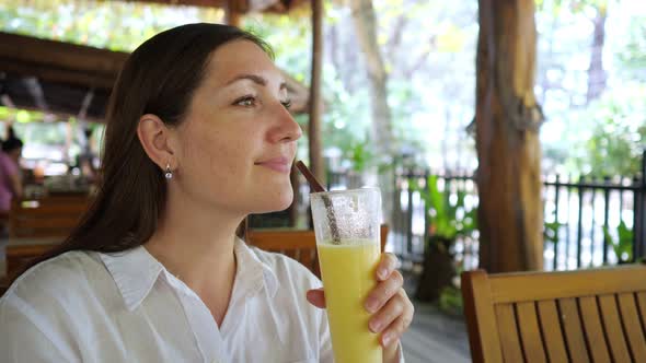 Woman in a White Shirt Drinks a Smoothie