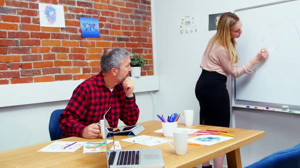 Business executives discussing over whiteboard during meeting