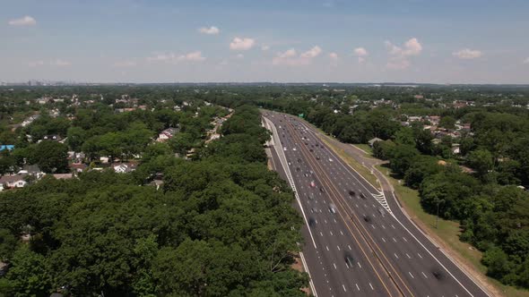 An aerial time lapse of a highway. It is a high angle shot showing the horizon and blue skies with w