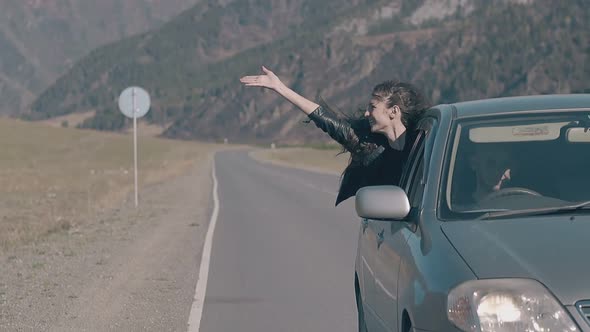 Car Drives Along Road with Pretty Girl Leaning Out of Window