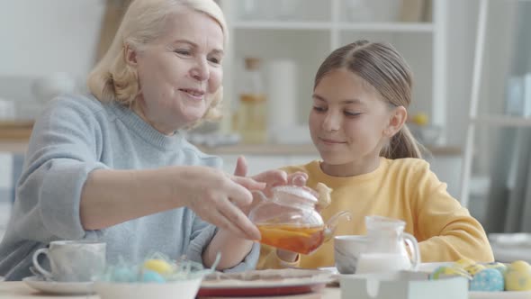 Little Girl and Grandmother Enjoying Tea and Easter Cookies