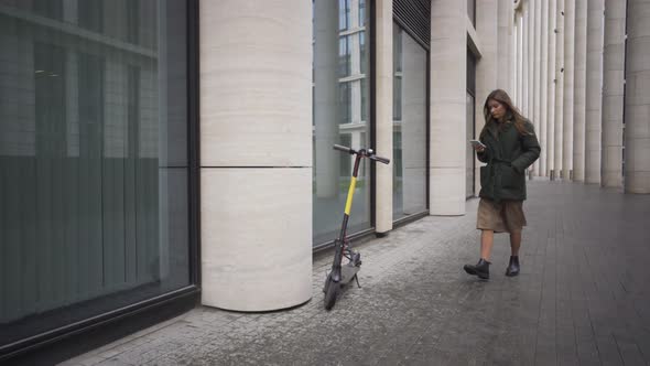 Attractive European Female Uses Her Phone To Unlock and Rent an Electric City Shared Scooter.