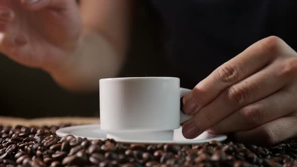 Coffee Cup and Coffee Beans. A White Cup of Evaporating Coffee on the Table with Roasted Bean. Slow