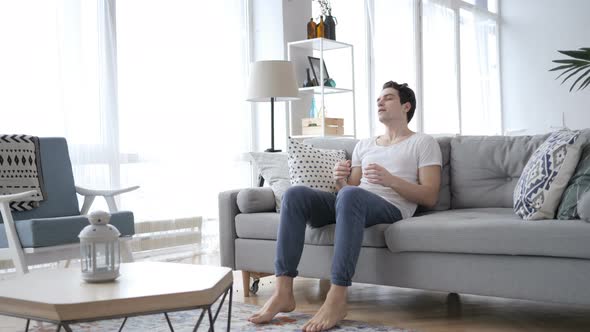 Young Man Coming To Room and Sitting on Sofa