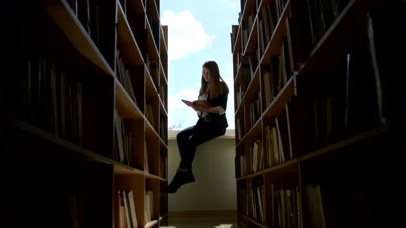 Girl Student Reading a Book on a Window Sill at the Library