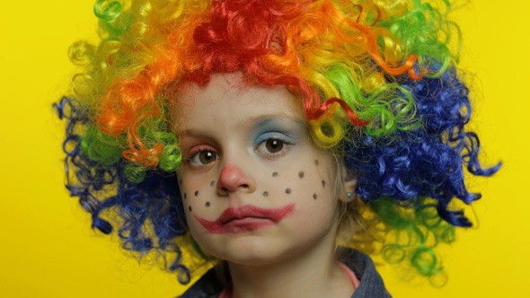 Little Child Girl Clown in Colorful Wig Tells Something Interesting. Having Fun, Smiling. Halloween