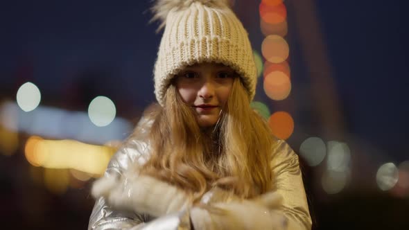 Freezed Caucasian Girl Rubbing Hands in Slow Motion Warming Outdoors with New Year Lights 