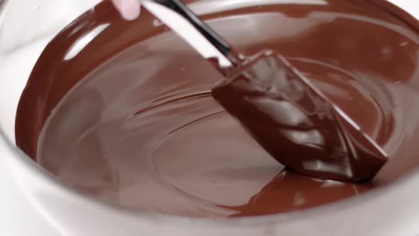 Silicone Spatula Stirs Dark Melted Chocolate in Glass Bowl Slow Mo Close Up