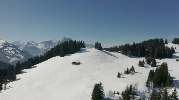 Aerial of single, remote cabin in snow covered mountainscape