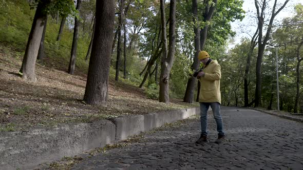 Travel Photographer Takes a Picture in a Park with Trees