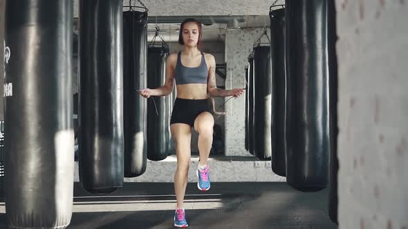 Athlete Jumping Rope on the Background of Boxing Bags