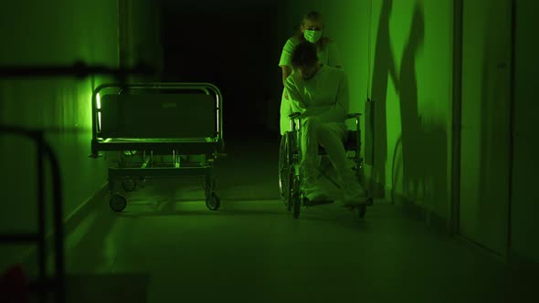 A Paramedic is Driving a Mad Male Patient in Wheelchair Down Corridor in Mental Hospital