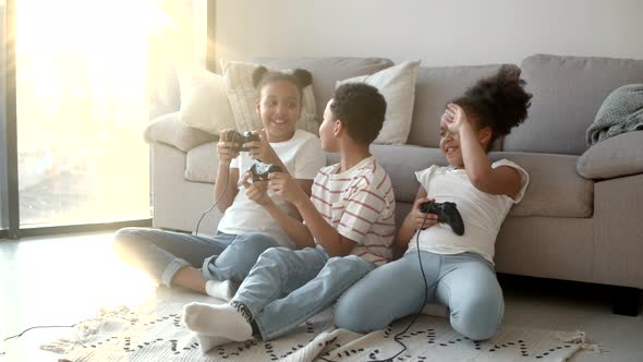 Happy African American Kids Playing Video Game with Joystick at Home