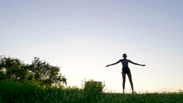 Young woman with headphones jumping jack on meadow