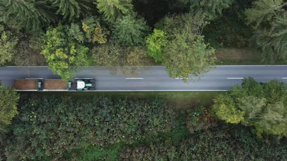 Tracking a tractor with two trailers from above, flying with a drone in a autumn avenue