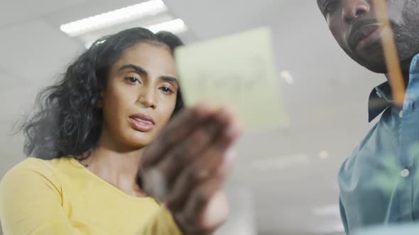 Video of focused diverse businesswoman and businessman brainstorming in office