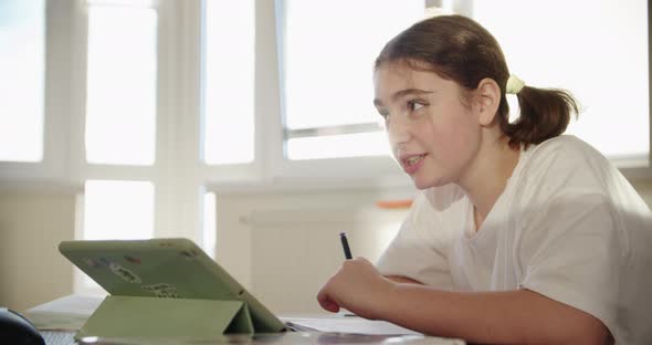 Girl Using Digital Tablet Technology Device in an Online Lesson Talking on Video Via Tablet