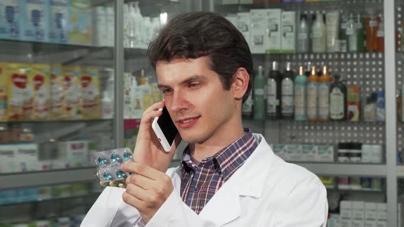 Clinician Talking on the Phone, Holding Two Blisters of Pills