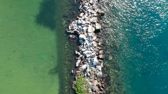 Aerial view of two different bodies of water divided by a man made break wall