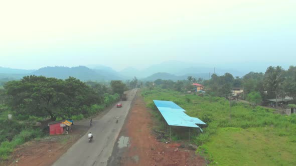 Rising drone shot from roadside rural India hills foggy haze