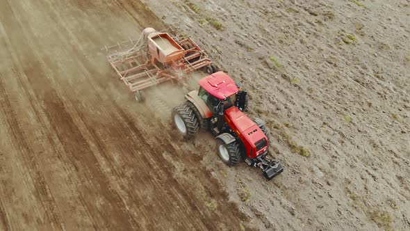 Farmer on a Tractor with a Container for Sowing Grain Crops Working in the Spring in the Field