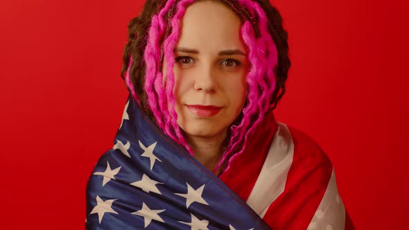 Young Woman Wrapped in American Flag on Red Background